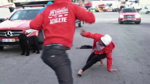 Handheld shot two professional surfers training capoeira outside on parking lot Stock Footage 155651761
