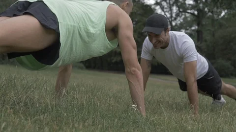 Handheld shot of two young men doing push-ups on lawn Stock Footage 114843506
