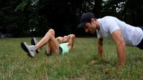 Handheld shot of two young men in sportswear exercising and stretching on grass Stock Footage 114879609