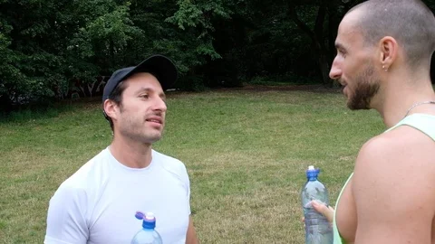 Handheld shot of two young men drinking water while standing Vídeo Stock 120425609