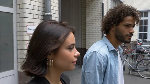 Handheld shot of two young people walking and talking in slow motion Vídeo Stock 114871697