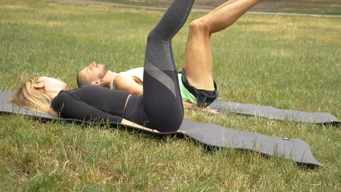 Handheld shot of two young people exercising on mats in public park Video stock 114874231