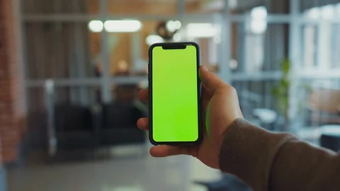 Handheld shot of vertical green screen smartphone mock-up indoors. Close-up Stock Footage 128247377