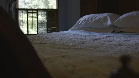 Handheld shot of vintage bed in dim lit room with balcony in background Stock Footage 208752536