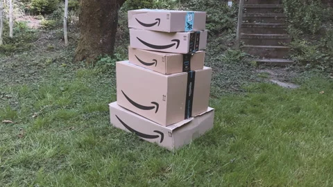 Handheld shot walking to multiple Amazon Prime cardboard boxes on a stack in Stock Footage 186191291