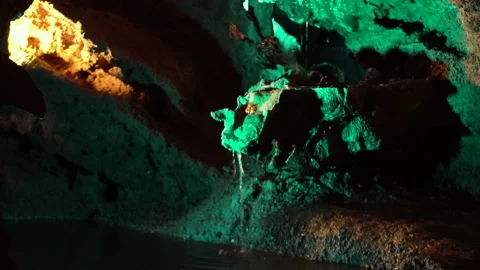 Handheld shot of water dripping down from rock in light up Moinhos Velhos cave Stock Footage 155256804