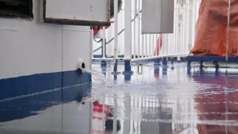 Handheld shot of water streaming from a scupper onto the ship’s deck, with a Stock Footage 299894254