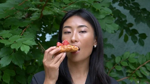Handheld shot of woman eats fruit pastry outdoors Video stock 114849771