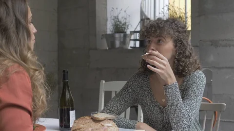 Handheld shot of women talking while eating bread and cheese with wine Stock Footage 114842328