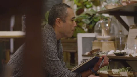 Handheld shot of worker with tablet computer examining plants at garden center Stock Footage