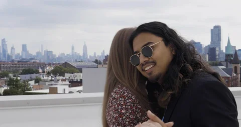 Handheld shot of young couple dancing on rooftop with skyline in background Stock Footage 120164807