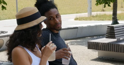 Handheld shot of young couple drinking and talking in park Stock Footage 120147056