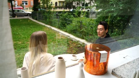 Handheld shot of young couple talking while sitting outside of cafe Stock Footage 114883906