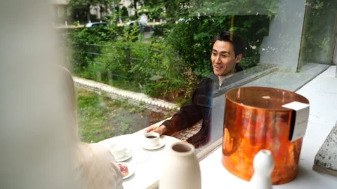 Handheld shot of young couple talking while sitting outside of cafe Stock Footage 114883909