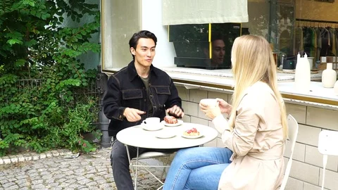 Handheld shot of young couple talking at table outside cafe in Berlin Stock Footage 114884405