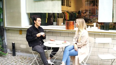 Handheld shot of young couple talking at table outside cafe in Berlin Stock Footage 114884407