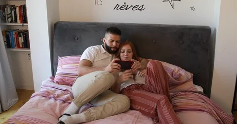 Handheld shot of young couple talking Selfie and talking in bed at home Stock Footage 120086088