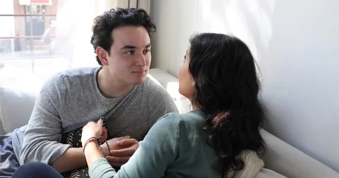 Handheld shot of young couple talking and smiling while sitting on sofa Stock Footage 120424347