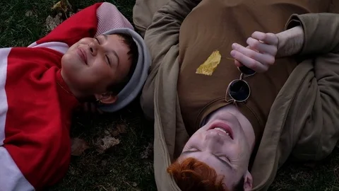 Handheld shot of young couple talking while lying on grass in the park Stock-Footage 120429904