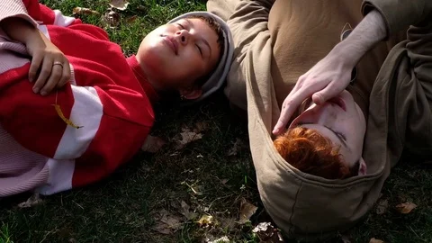 Handheld shot of young couple talking while lying on grass in the park 스톡 동영상 120433026