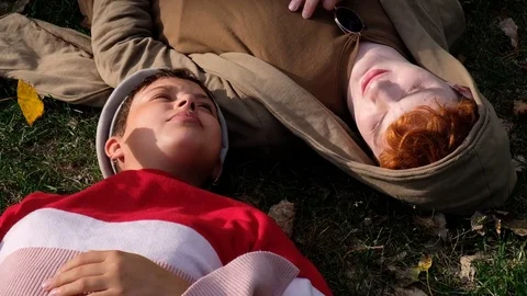 Handheld shot of young couple talking while lying on grass in the park Stock Footage 120434171