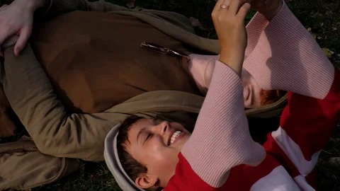 Handheld shot of young couple talking while lying on grass in the park Stock-Footage 120434836