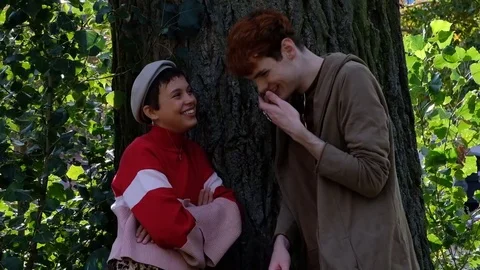 Handheld shot of young couple talking while standing by the tree trunk Vídeo Stock 120436660