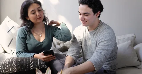 Handheld shot of young couple using smart phone together and talking at home Stock Footage 120429873