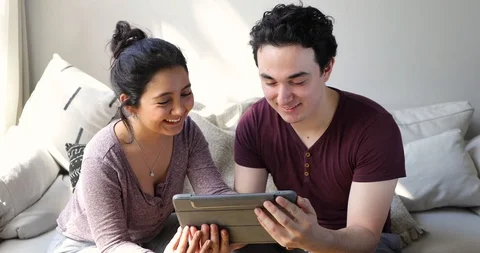 Handheld shot of young couple using digital tablet while sitting in living room Video stock 120430156