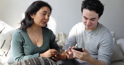 Handheld shot of young couple using smart phone and talking at home Stock Footage 120432250
