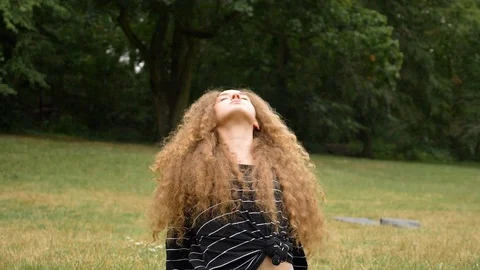 Handheld shot of young curly haired woman doing yoga in park in slow motion 스톡 동영상 114873741