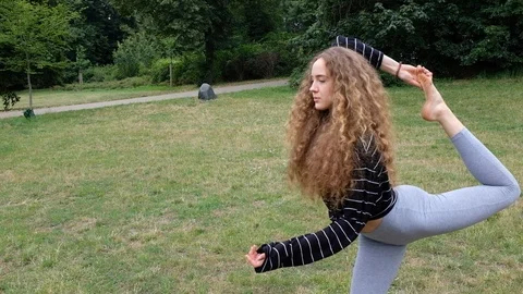 Handheld shot of young curly haired woman doing yoga in park Stock-Footage 120427933