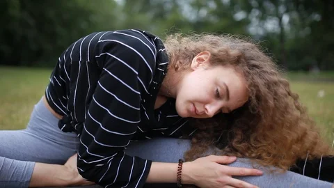 Handheld shot of young curly haired woman stretching in park 스톡 동영상 120429885