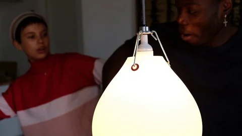 Handheld shot of young friends dancing by lighting equipment in living room Stock Footage 120431035