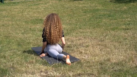 Handheld shot of young lady doing stretching exercise in the park Video stock 114849977