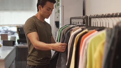 Handheld shot of young man browsing collection of clothes Stock Footage 114875436