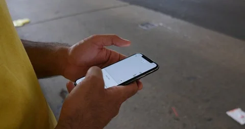 Handheld shot of young man browsing his smart phone on sidewalk Stock Footage 120149623
