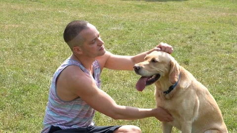 Handheld shot of young man caressing his pet dog in the park Video stock 114849985