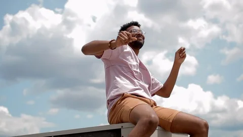 Handheld shot of a young man dancing while sitting in the metal Stock Footage 114880609