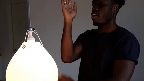 Handheld shot of young man dancing in front of illuminated lighting equipment 스톡 동영상 120433686