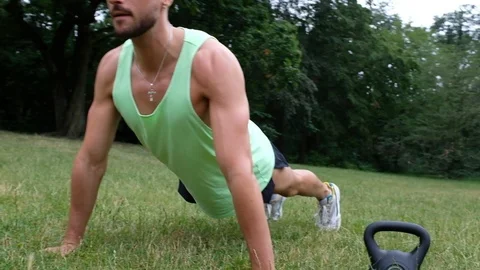 Handheld shot of young man doing Push-up on grass 스톡 동영상 120424598