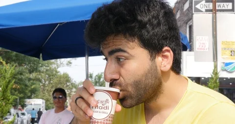 Handheld shot of young man drinking at outdoor table in city Stock Footage 120149456