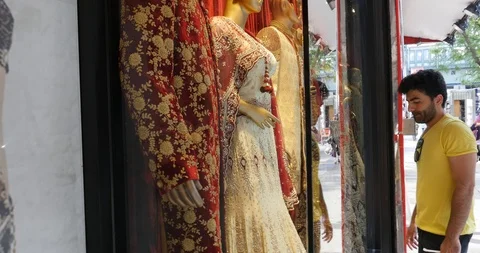 Handheld shot of young man looking at traditional clothes through window display Stock Footage 120043814