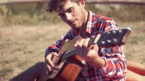 Handheld shot of young man playing guitar at camp Stock Footage 55188080