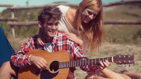 Handheld shot of young man playing guitar at camp Stock Footage 55191126