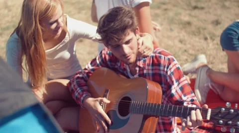Handheld shot of young man playing guitar at camp Stock Footage 55196374