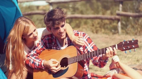 Handheld shot of young man playing guitar at camp Stock Footage 55196735