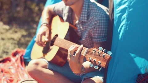Handheld shot of young man playing guitar at camp Stock Footage 55259605