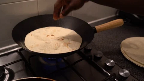 Handheld shot of a young man preparing tortilla for burritos in the kitchen Stock Footage 114880872