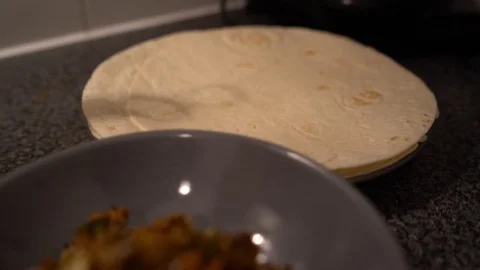 Handheld shot of a young man preparing tortilla for burritos in the kitchen Stock Footage 114880874